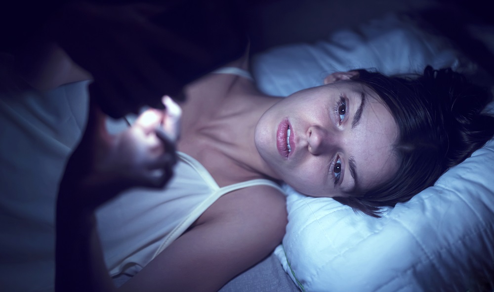 Young woman in bed and can't sleep, on phone