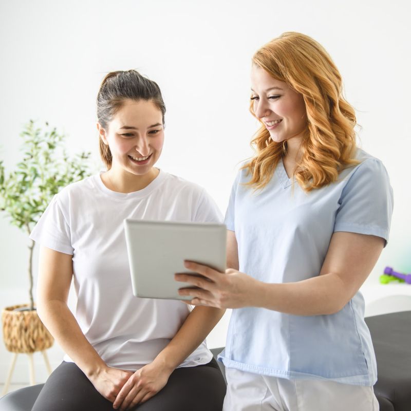 woman physical therapist showing patient ipad