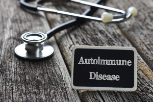 Medical Concept- Autoimmune Disease word written on blackboard with Stethoscope on wood background