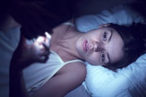 Young woman in bed and can't sleep, on phone