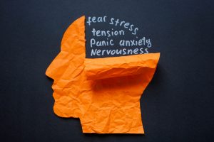 Torn paper head and the words fear stress and anxiety. Mental health struggles and emotional distress.